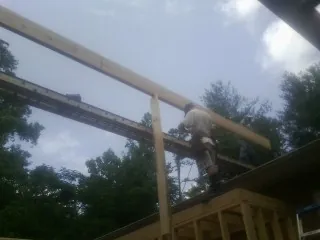 Carpenter setting a ridge beam over a new addition frame — Ice Dam Removal by Roofing Brothers in Burleson
