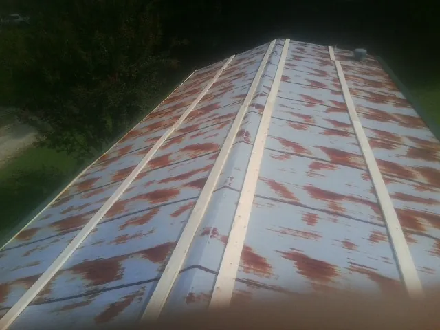 Rusted metal roof panels with new wood purlins before replacement in Burleson