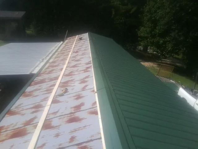Old rusted panels beside newly installed green metal roofing — Wind Damage Roof Repair by Roofing Brothers in Burleson