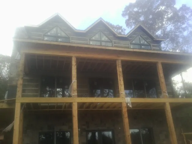 Dormers and porch framing on a large log home under construction — Roof Coating work by our crew in Burleson
