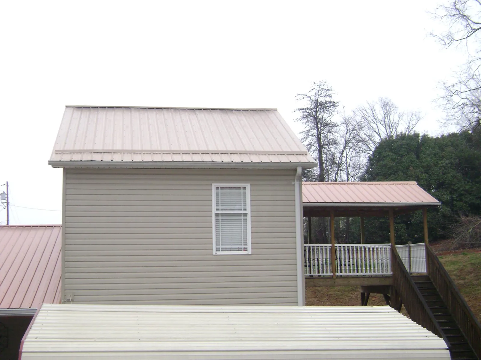 Tan metal roofs on a two story addition and attached porch, from a Roof Replacement job in Burleson